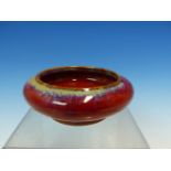 A CHINESE FLAMBE GLAZED SHALLOW BOWL, THE FLATTENED BUN SHAPE WITH THE RED GLAZE WITH LAVENDER