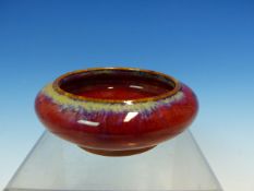 A CHINESE FLAMBE GLAZED SHALLOW BOWL, THE FLATTENED BUN SHAPE WITH THE RED GLAZE WITH LAVENDER