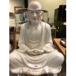 A CHINESE FIGURE OF A MEDITATING MONK SEATED CROSS LEGGED AND WITH HIS HANDS CLASPED IN THE LAP OF
