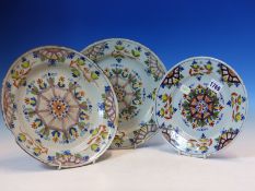 A PAIR AND ANOTHER SMALLER ENGLISH DELFT POLYCHROME PLATES, EACH WITH A CENTRAL SEVEN SIDED WHEEL