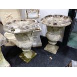 A PAIR OF RECONSTITUTED STONE GARDEN URNS DECORATED WITH CLASSICAL FIGURES.