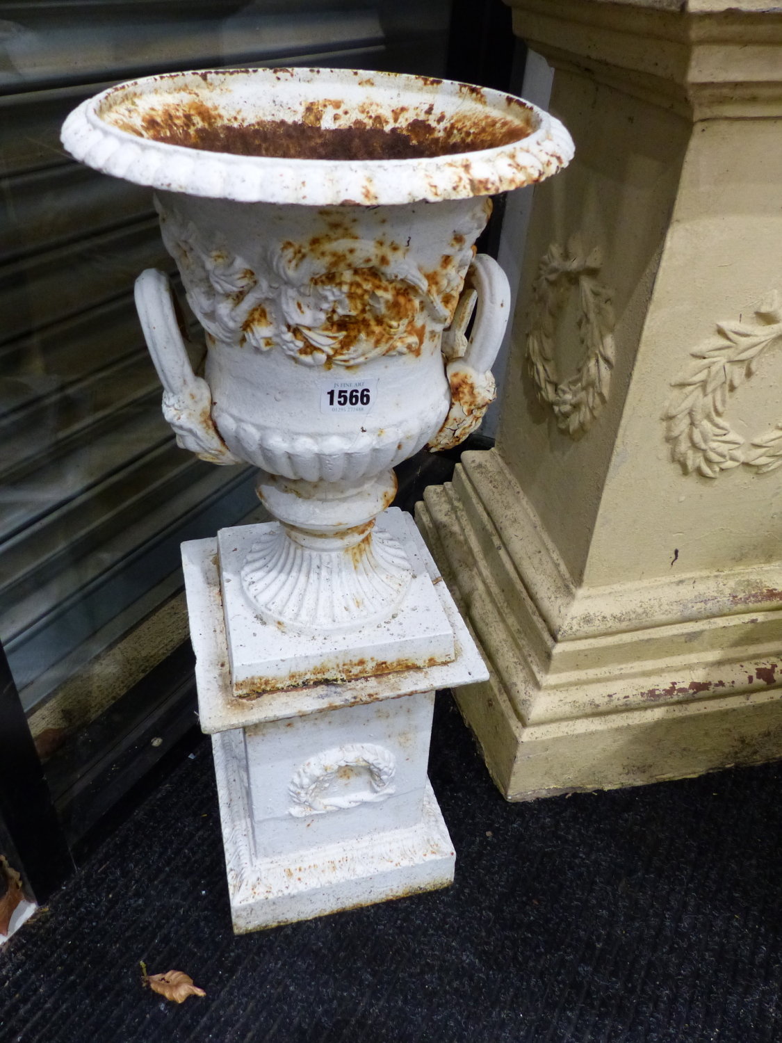 A PAIR OF VICTORIAN STYLE SMALL CAST IRON URNS ON PEDESTAL BASES AND A PAIR OF ROCOCO STYLE IRON
