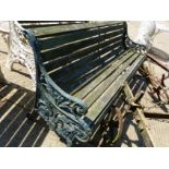 AN ANTIQUE GREEN PAINTED GARDEN BENCH WITH CAST IRON ENDS.