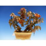 A CHINESE HARDSTONE FLOWERING TREE IN AN OCHRE AND GREY HARDSTONE ELONGATED OVAL TROUGH. H 21cms.
