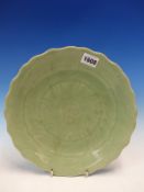 A CHINESE CELADON DISH INCISED TO DEPICT A LOTUS FLOWER WITHIN THE WAVY RIM. Dia. 26cms.