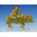 A CHINESE GREEN HARDSTONE WATER BUFFALO RIDDEN BY A BOY WITH A BROWN RIMMED HAT. W 19cms.