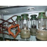 FOUR TILLY LAMPS AND TWO SADDLE RACKS.