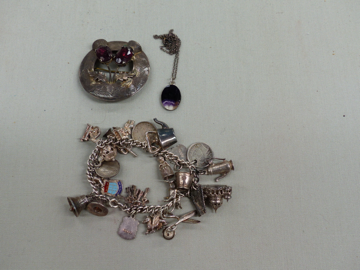 A SILVER CHARM BRACELET, A SILVER SCOTTISH THISTLE BROOCH, AND A BLUE JOHN SILVER CASED PENDANT.