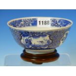 A CHINESE BLUE AND WHITE BOWL WITH WOOD STAND, THE EXTERIOR PAINTED WITH ALTERNATING GARDEN AND