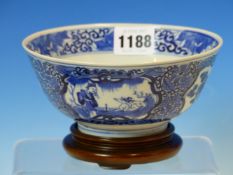 A CHINESE BLUE AND WHITE BOWL WITH WOOD STAND, THE EXTERIOR PAINTED WITH ALTERNATING GARDEN AND