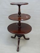 A GEORGIAN MAHOGANY DUMB WAITER, THE THREE TIERS REVOLVING ON BALUSTERS ON A TRIPOD WITH LONG NOSED