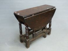 AN EARLY OAK OVAL FLAP TOP TABLE SUPPORTED ON BOBBIN TURNED LEGS JOINED BY