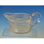 AN EARLY 19th C. CUT GLASS JUG, THE FACETTED INVERTED RIM ABOVE A BODY OF OVAL SECTION CUT WITH A