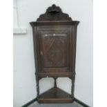 A 19th C. OAK CORNER CUPBOARD, A SMALL SHELF TO THE TOP OF THE WAVY EDGED GALLERY ABOVE A DOOR