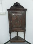 A 19th C. OAK CORNER CUPBOARD, A SMALL SHELF TO THE TOP OF THE WAVY EDGED GALLERY ABOVE A DOOR