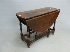 AN ANTIQUE OAK OVAL FLAP TOP TABLE SUPPORTED ON BALUSTER TURNED LEGS JOINED BY STRETCHERS ABOVE THE