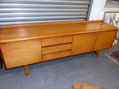 A TEAK SIDEBOARD, THE RECTANGULAR TOP SWEPT UP AT THE BACK AND ABOVE THREE DRAWERS AND CUPBOARDS