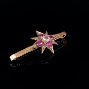 AN ANTIQUE VICTORIAN RUBY AND DIAMOND STAR BURST BAR BROOCH. LENGTH 5cms, STAR 3cms. WEIGHT 4.9grms.