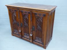 A 19th.C. OAK GOTHIC REVIVAL CABINET WITH THREE CARVED PANEL DOORS. 129 x 53 x 102cms (H).