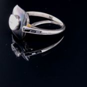 AN ART DECO STYLE DIAMOND AND BLACK ONYX SET 18CT WHITE GOLD RING. THE SINGLE ROUND BRILLIANT CUT TO