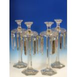 A SET OF FOUR BACCARAT STYLE CLEAR GLASS HEXAGONAL COLUMN LUSTRE CANDLESTICKS, THE BEAD AND