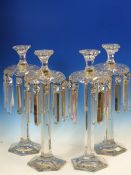 A SET OF FOUR BACCARAT STYLE CLEAR GLASS HEXAGONAL COLUMN LUSTRE CANDLESTICKS, THE BEAD AND