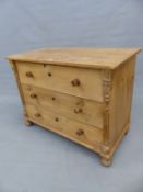 AN ANTIQUE PINE CHEST OF THREE LONG DRAWERS BETWEEN FLUTED PILASTERS AND ON BUN FEET.