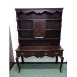 AN OAK DRESSER WITH ENCLOSED BACK OF SHELVES ABOUT A CENTRAL CUPBOARD THE TWO DRAWER BASE WITH