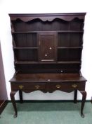 AN OAK DRESSER WITH ENCLOSED BACK OF SHELVES ABOUT A CENTRAL CUPBOARD THE TWO DRAWER BASE WITH