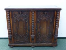 AN OAK BAROQUE STYLE SIDE CABINET, THE DOORS CARVED WITH ANGELS HEADS OVER INLAID STARS