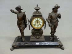 AN ANSONIA CLOCK FLANKED BY TWO SPELTER CAVALIER FIGURES STANDING ON AN IRON PLINTH ON PAW FEET. W