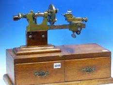 M COHEN LEEDS, A BRONZE AND STEEL WATCHMAKERS LATHE MOUNTED ON AN OAK BOX WITH TWO DRAWERS