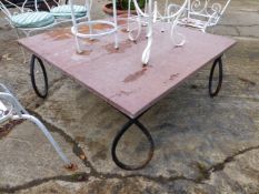 A WROUGHT IRON BASED COFFEE TABLE WITH RED MARBLE TOP.