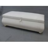 A WHITE UPHOLSTERED OTTOMAN, THE RECTANGULAR LID HINGED OVER BOMBE SIDES. W 127 x D 54 x H 45cms.