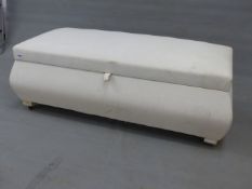 A WHITE UPHOLSTERED OTTOMAN, THE RECTANGULAR LID HINGED OVER BOMBE SIDES. W 127 x D 54 x H 45cms.