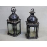 A PAIR OF BLACK PAINTED METAL LANTERNS WITH PANELS OF GLASS TO THE FOUR SIDES AND THE SQUARE