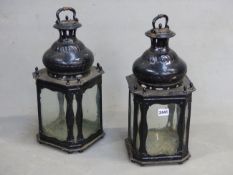 A PAIR OF BLACK PAINTED METAL LANTERNS WITH PANELS OF GLASS TO THE FOUR SIDES AND THE SQUARE