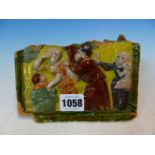 A EUROPEAN TILE FRAGMENT MOULDED IN RELIEF WITH A MEDIAEVAL MAN EXPELLING A WOMAN AND CHILD WHILE