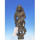 AN INDIAN BRONZE OF A FEMALE DEITY STANDING AND ONCE HOLDING AN ATTRIBUTE BEFORE HER WITH BOTH