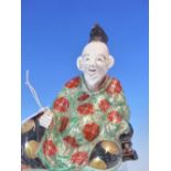 A JAPANESE PORCELAIN FIGURE OF A SEATED ELDERLY DIGNITARY, HIS GREEN ROBE WITH IRON RED ROUNDELS
