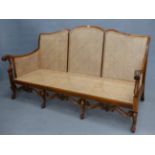 AN EARLY 20th.C. BERGERE CANE BACK THREE SEAT SOFA ON CARVED CAROLEAN STYLE LEGS AND STRETCHER,