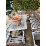 A TEAK GARDEN BENCH AND TWO ARMCHAIRS EACH WITH FLORAL CARVED TOP RAILS TOGETHER WITH A TEAK TABLE