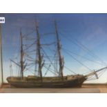 A SHIPS MODEL IN GLAZED BRONZE EDGED CASE, THE THREE RIGGED MASTS OVER A DECK WITH HATCHES, THE