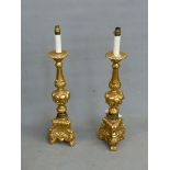 A PAIR OF GILT COMPOSITION BAROQUE STYLE CANDLESTICK LAMPS, THE BALUSTER COLUMNS ABOVE FRUIT KNOPS