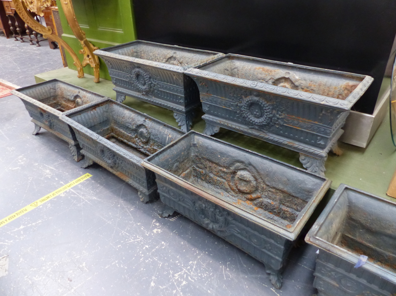 A HARLEQUIN SET OF SIX ANTIQUE IRON PLANTERS, THE RECTANGULAR RIMS OVER FLUTED BANDS AND CENTRAL