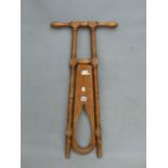 A VINTAGE MAHOGANY BOOT JACK, THE PIERCED PANEL FOLDING BETWEEN TWO TURNED COLUMNS TOPPED BY HANDLE