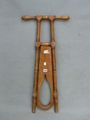 A VINTAGE MAHOGANY BOOT JACK, THE PIERCED PANEL FOLDING BETWEEN TWO TURNED COLUMNS TOPPED BY HANDLE