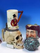 A GERMAN PORCELAIN SKULL TANKARD, A DOULTON SIMON CELLARER MASK JUG, A CHILDS CERAMIC HEAD, A