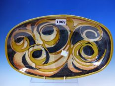 A WOOLMILL POTTERY ROUNDED RECTANGULAR BOWL WITH OCHRE SCROLLS ON A BLACK GROUND. W 32cms.