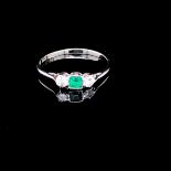 AN 18ct WHITE GOLD AND PLATINUM EMERALD AND DIAMOND THREE STONE RING. THE CENTRAL EMERALD A PRINCESS